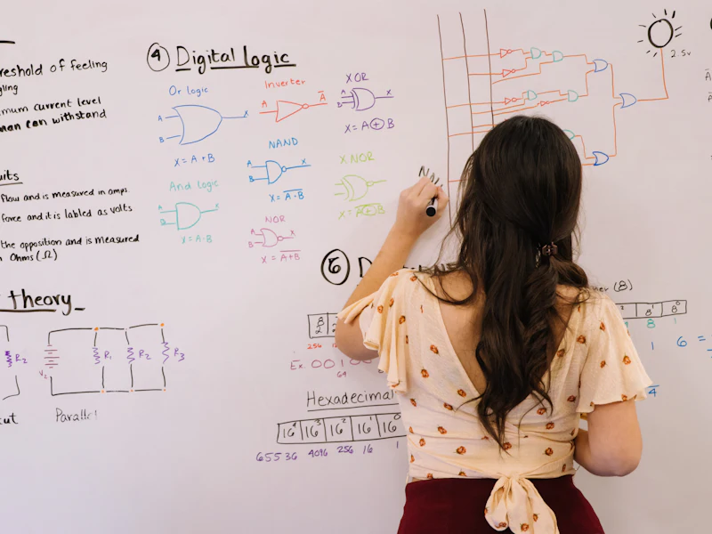 A student working through digital logic on a whiteboard